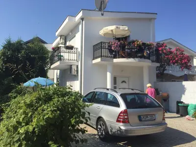 a car parked in front of a white house at Apartment Nafija. No 2 in Donji Štoj