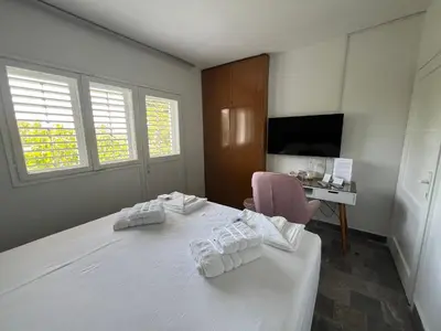 a bedroom with a white bed with a chair and a desk at Casa Cristiano in Sutomore