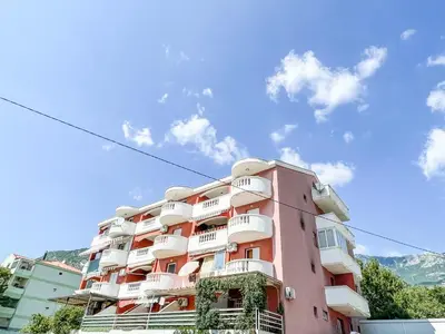 a pink building with white balconies on it at Apartment Anita - Budva in Budva