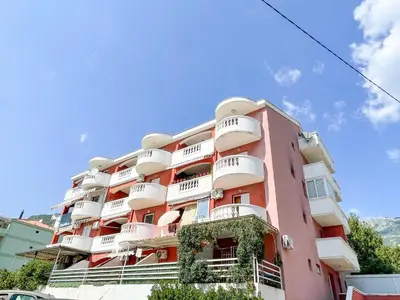 a pink apartment building with white balconies on it at Apartment Anita - Budva in Budva