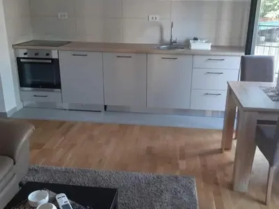 a kitchen with white cabinets and a table and a sink at Apartman Podgorica in Podgorica