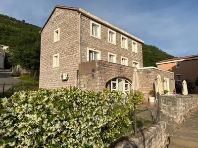 a brick building with a bush in front of it at Apartments Pavlovic in Petrovac na Moru