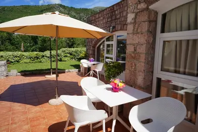 a patio with a white table and chairs and an umbrella at Apartments Pavlovic in Petrovac na Moru