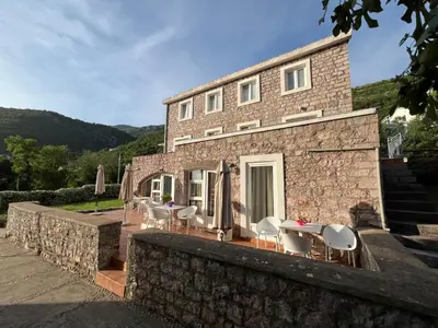 a brick building with tables and chairs in front of it at Apartments Pavlovic in Petrovac na Moru
