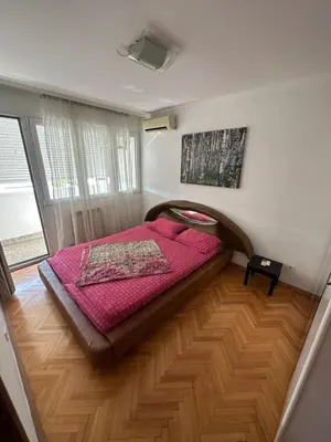 a bedroom with a bed on a wooden floor at Large Centre apartment in Podgorica