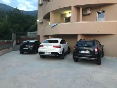 two cars parked in a parking lot next to a building at Alessandra Apartments in Sveti Stefan