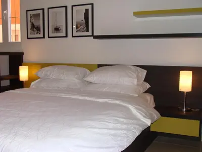 a large white bed with three pictures on the wall at Alessandra Apartments in Sveti Stefan