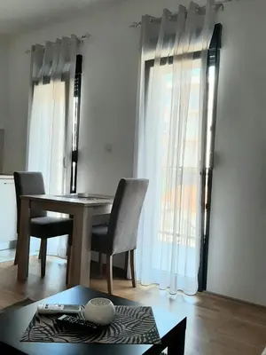 a dining room with a table and chairs and a window at Apartment Podgorica in Podgorica