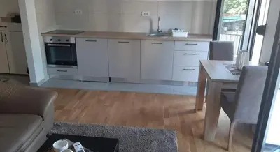 a kitchen with white cabinets and a table and a couch at Apartment Podgorica in Podgorica