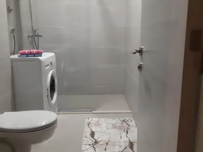 a white bathroom with a toilet and a sink at Apartment Podgorica in Podgorica