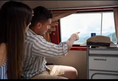 a man and a woman looking out the window of a train at Mobile home - Alpha Campers Montenegro - Our Red Westfalia Bus in Podgorica