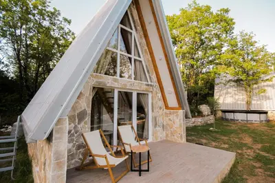 a tiny house with a large window and chairs on a deck at Vukova dolina apartments in Cetinje