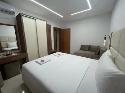 a bedroom with a large white bed and a couch at Arbneshi Apartments in Ulcinj