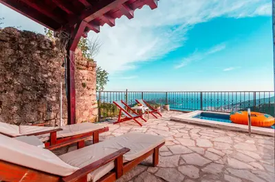 a patio with tables and chairs and a swimming pool at Villa Vistamar Lapcici in Budva