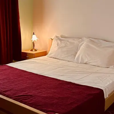 a bed with white sheets and a red blanket at Villa Vistamar Lapcici in Budva