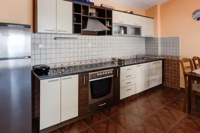 a kitchen with white cabinets and a stainless steel refrigerator at Villa Vistamar Lapcici in Budva