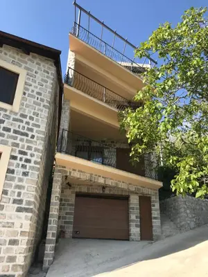 a brick house with a garage and a balcony at Villa Ladera Lapcici in Budva
