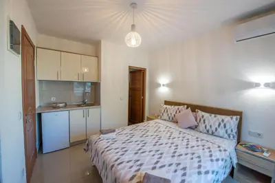 a bedroom with a large bed and a kitchen at M&M Apartments in Utjeha