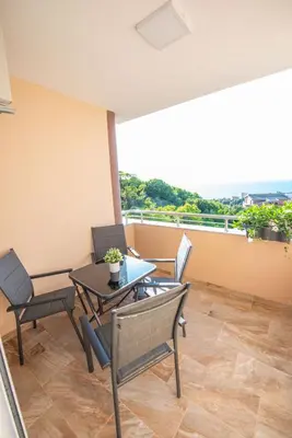 a room with a table and chairs and a balcony at M&M Apartments in Utjeha