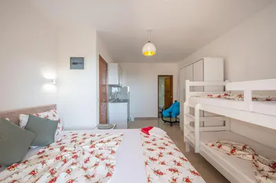 a white bedroom with two bunk beds and a kitchen at M&M Apartments in Utjeha