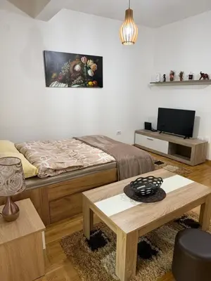 a bedroom with a bed and a table and a tv at Kropa apartman in Podgorica