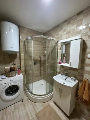 a bathroom with a shower and a sink and a washing machine at Kropa apartman in Podgorica