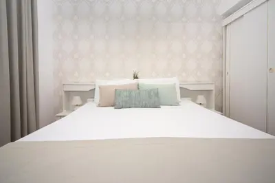 a bed with white sheets and pillows in a bedroom at Apartments Adeona in Tivat