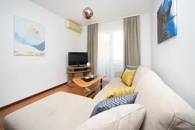 a living room with a white couch and a tv at Apartments Adeona in Tivat