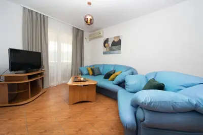 a living room with a blue couch and a television at Apartments Adeona in Tivat