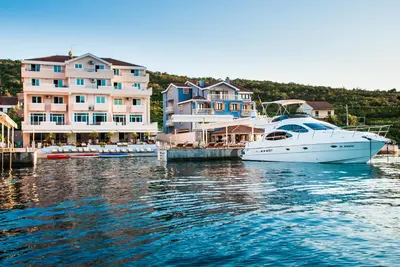 a white boat docked in a harbor with houses at Apartments Adeona in Tivat