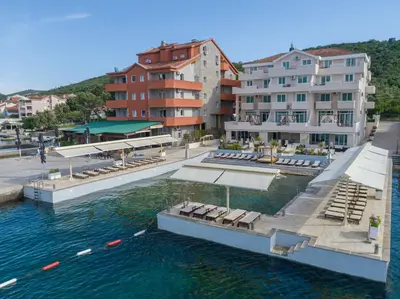 a pool of water with lounge chairs and buildings at Apartments Adeona in Tivat
