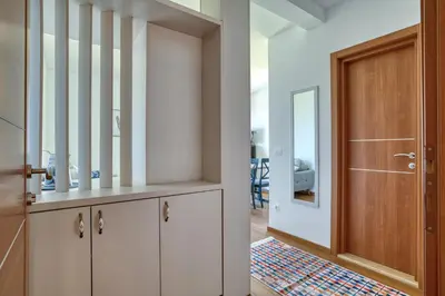 a hallway with white cabinets and a wooden door at Vila Aria vista in Petrovac na Moru
