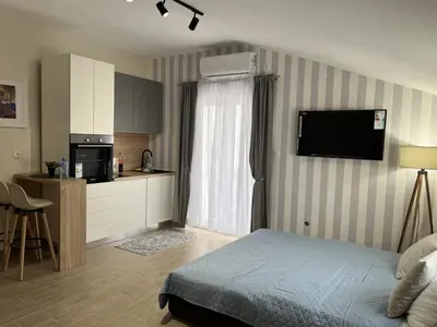 a bedroom with a bed and a kitchen with a television at Apartment Quince in Budva