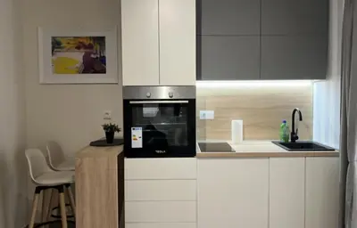 a kitchen with white cabinets and a black microwave at Apartment Quince in Budva