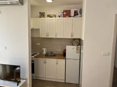 a small kitchen with white cabinets and a refrigerator at Golden parrot in Podgorica