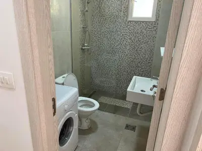 a bathroom with a toilet and a sink and a washing machine at Golden parrot in Podgorica