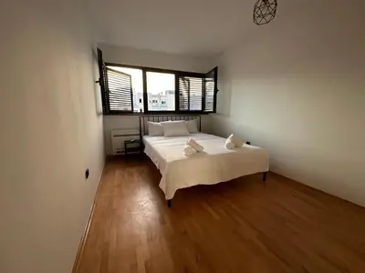 a bedroom with a bed with white sheets and a window at City Oasis - two bedroom apartment in Blok 5 in Podgorica