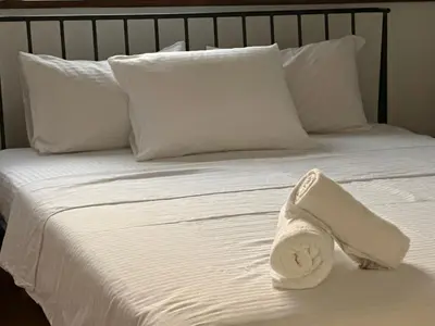 a white bed with white pillows and a towel on it at City Oasis - two bedroom apartment in Blok 5 in Podgorica