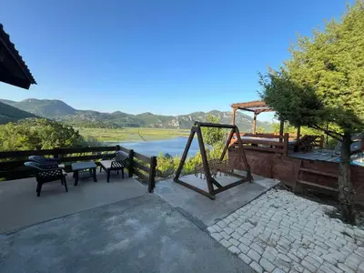 a patio with a table and chairs and a view of a river at LAKE VIEW PREVLAKA in Cetinje