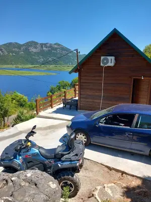 a motorcycle parked next to a car in front of a house at LAKE VIEW PREVLAKA in Cetinje