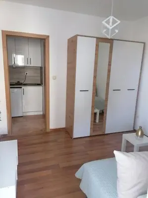 a room with a bed and a kitchen with a mirror at Smile in Becici