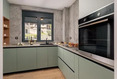 a kitchen with white cabinets and a large microwave at Berge Apartments in Kotor