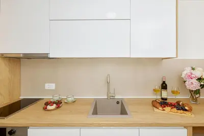 a kitchen counter with a sink and some bottles of wine at Berge Apartments in Kotor
