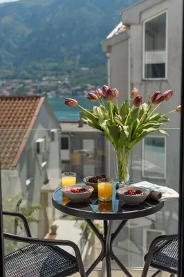 a table with a vase of flowers on a balcony at Berge Apartments in Kotor