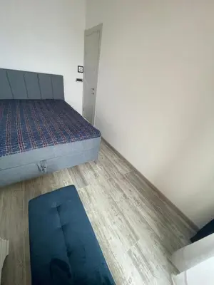 a bedroom with a bed and a blue rug at Miločer Apartman Beograd in Pržno