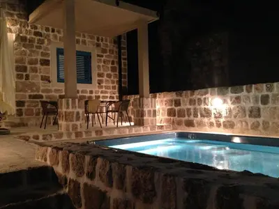a swimming pool in a stone walled yard at night at Villa Old Olive in Budva