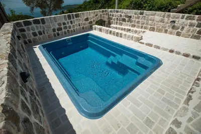 a blue swimming pool in a stone wall at Villa Old Olive in Budva