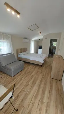 a bedroom with a bed and a couch and wooden floors at Superb Apartments Virpazar in Virpazar