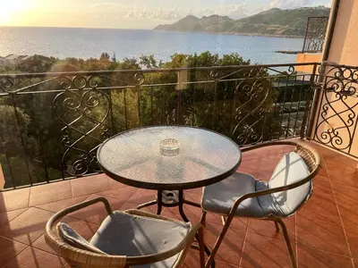 a table and chairs on a balcony with a view of the ocean at Apartment Sea View Dobra Voda in Dobra Voda