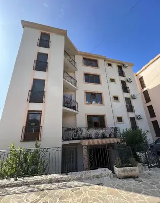 a tall white building with balconies on it at Apartment Sea View Dobra Voda in Dobra Voda